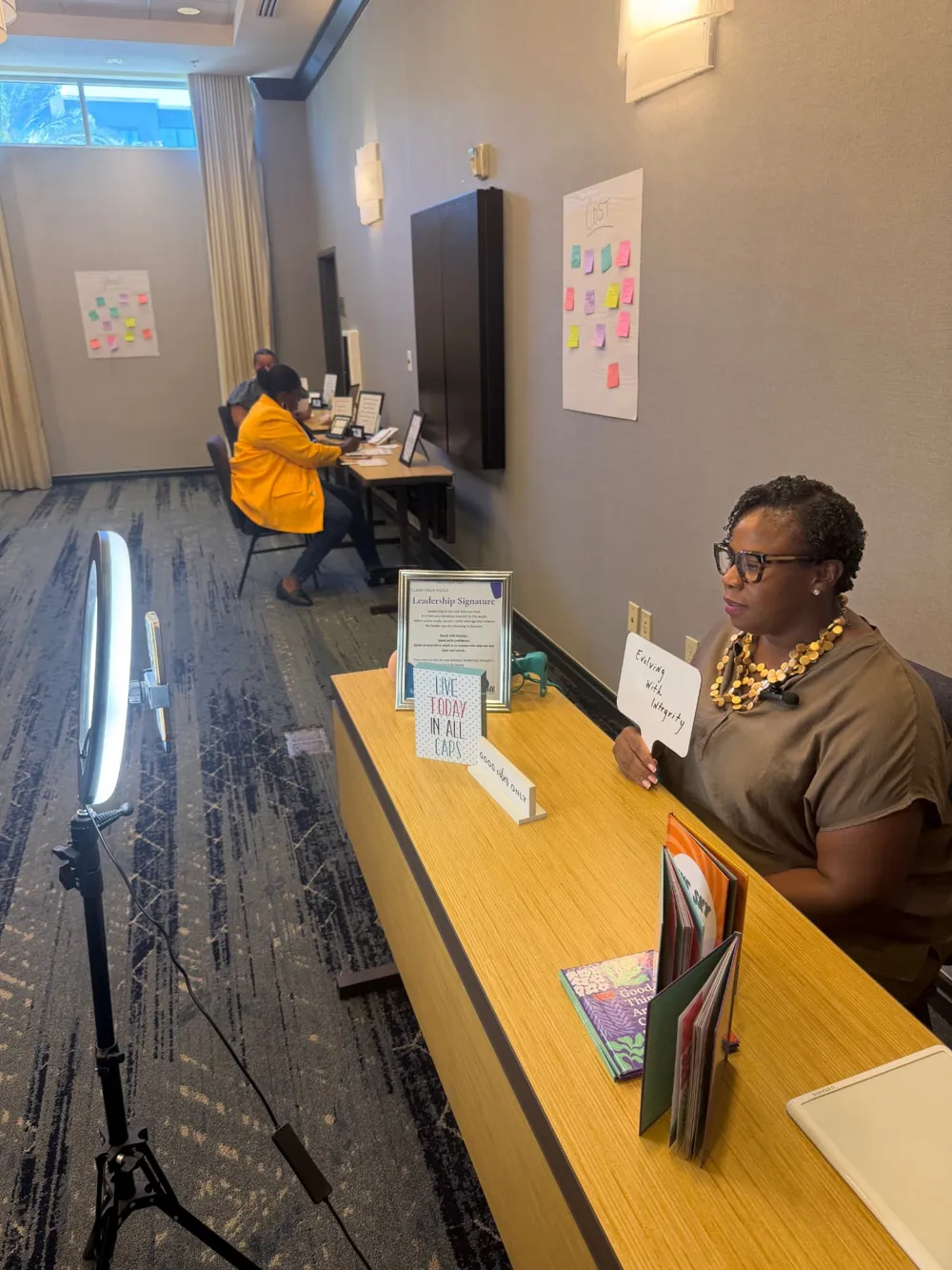 A participant holding a card reading “Evolving with Integrity” while recording her Leadership Signature